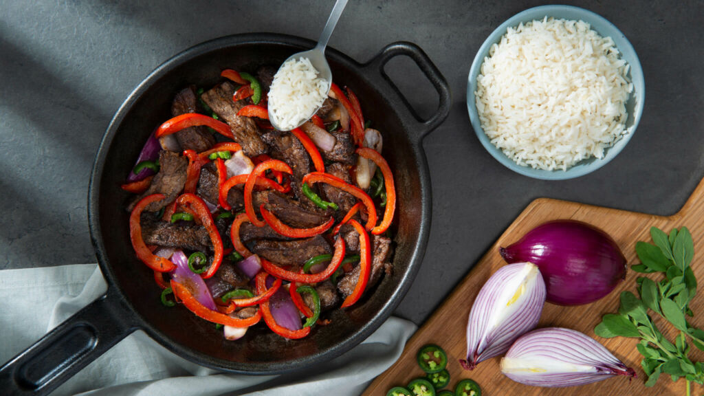 Mexican spiced beef in a pan with peppers and red onion