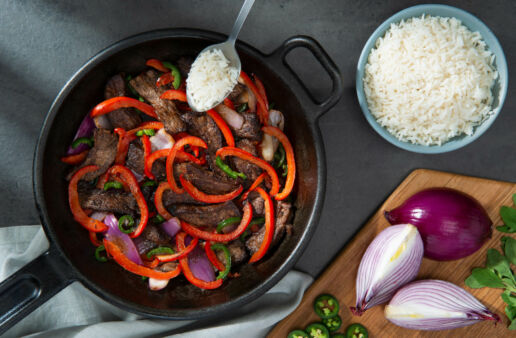 Mexican spiced beef in a pan with peppers and red onion