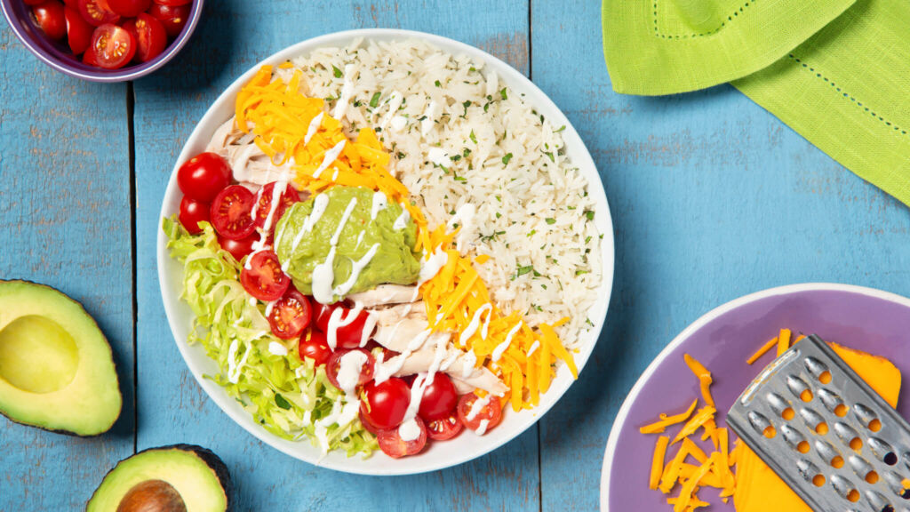 Burrito bowl with cilantro lime rice, cheddar cheese, shredded chicken and guacamole