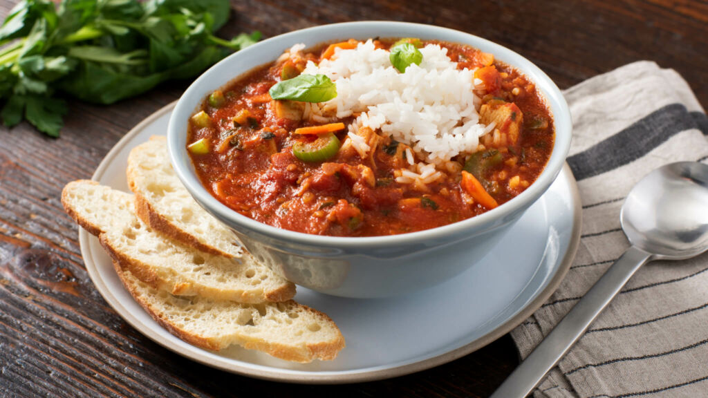 White bowl filled with tomato soup with rice and basil topped with cheese