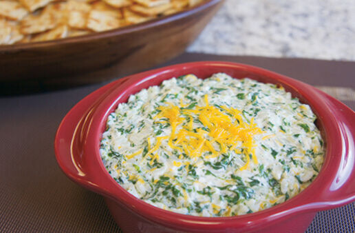 Cheesy spinach and rice dip in a red microwave bowl