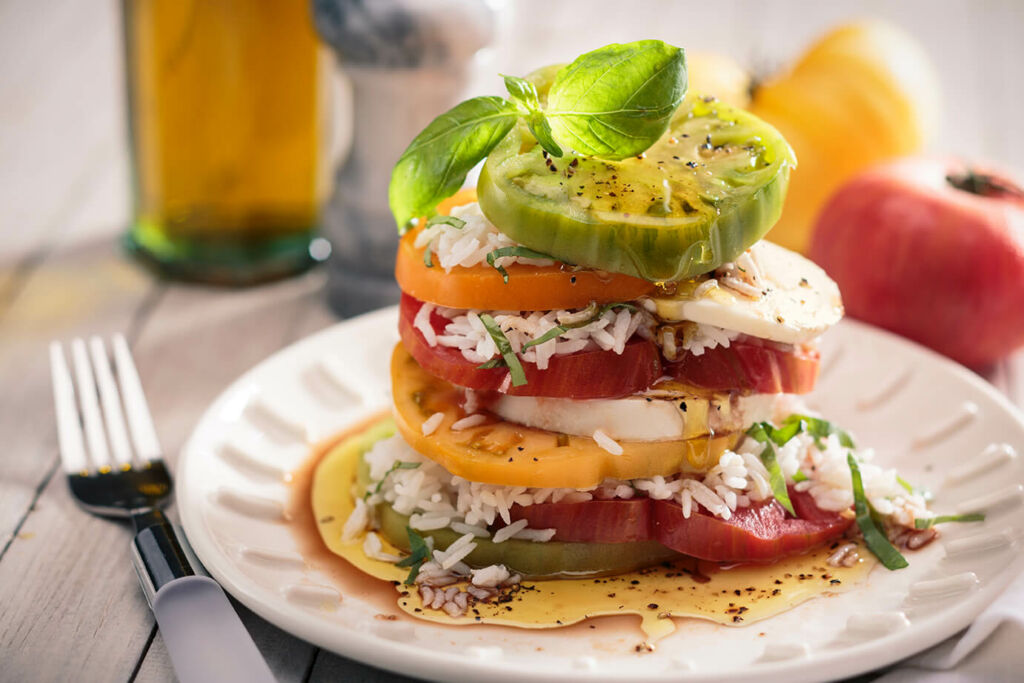 Layered rice caprese salad with tomatoes, mozzarella and basil