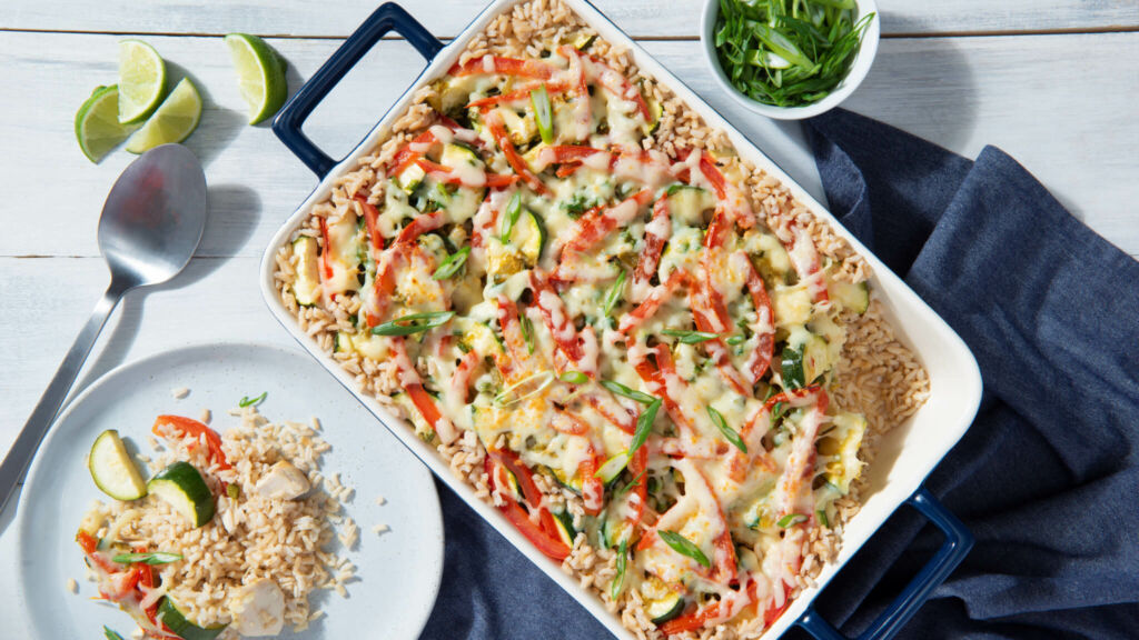 White casserole and plate with brown rice and vegetables topped with grated cheese