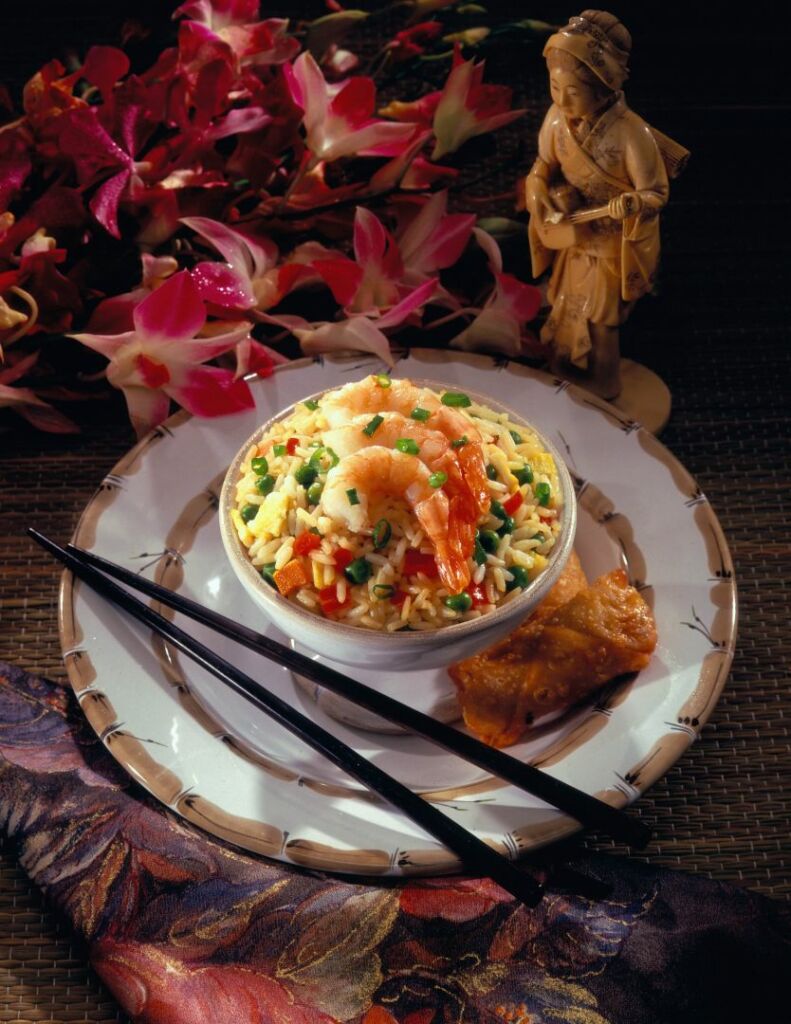Chopsticks and bowl with fried rice, peas, shrimp and pork